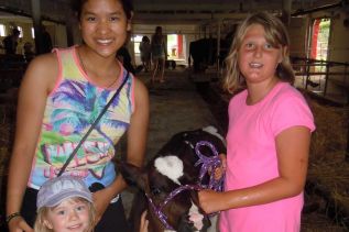 Arada Limsirichai, Lucy Parsons and Sarah Campbell with 3-month-old dairy calf Reese at Sonset Farm near Inverary